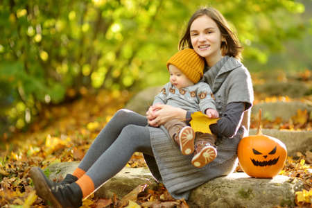 Cute big sister cuddling with her baby brother. Adorable teenage girl holding her new baby boy brother. Kids with large age gap. Big age difference between siblings. Big family.の写真素材