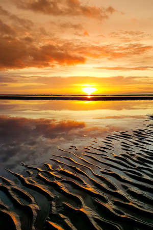 Beautiful sunset colors over the coastline of Allerdale district in Cumbria, UK. Sun setting over the shore of Allonby bay on autumn evening.の写真素材