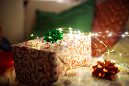 Wrapped Christmas gift boxes decorated with bows sitting on a sofa. Christmas lights wrapped around presents.の写真素材