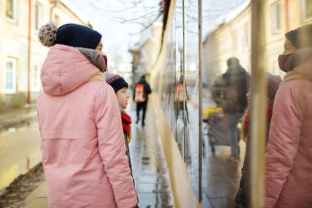 Two young girls having fun on beautiful winter day in Uzupis district in Vilnius, Lithuania. Cute...