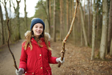 Cute young girl having fun during forest hike on beautiful winter day. Active family leisure with kids. Family fun.の写真素材