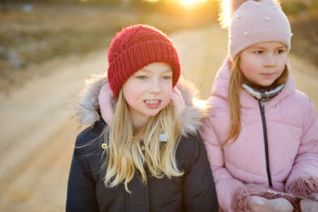 Two cute young sisters having fun during forest hike on beautiful early spring day. Active family leisure with kids. Family fun.の写真素材