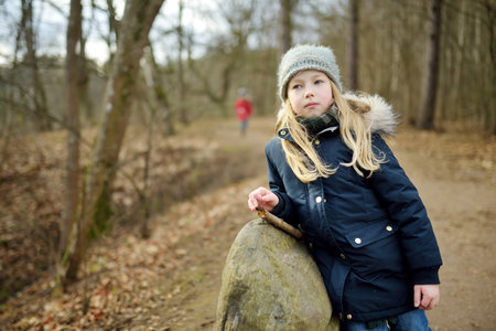 Cute young girl having fun during forest hike on beautiful winter day. Active family leisure with kids. Family fun.の写真素材