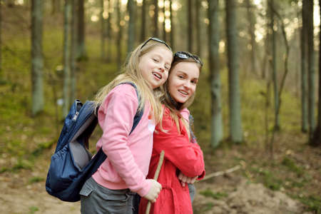 Two cute young sisters having fun during forest hike on beautiful early spring day. Active family leisure with kids. Family fun.の写真素材