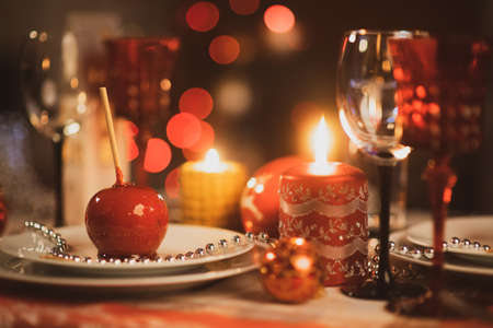 Beautiful table setting for Christmas party or New Year celebration at home. Cozy room with a fireplace and Christmas tree in a background. Xmas time with family and friends.の写真素材