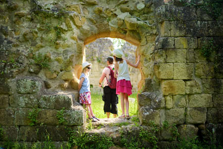 Family of three exploring old caves dug into the tuff rock and used for human habitation in ancient times. Citta del Tufo archaeological park. Sorano, Sovana, Tuscany, Italy.の写真素材