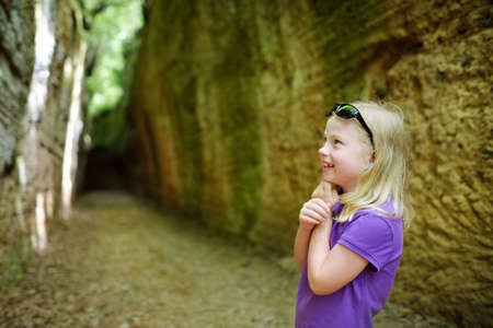 Girl exploring Etruscan Le Vie Cave (Via Cava), the path connecting ancient necropolis and settlements in the area between Sovana and Sorano. Citta del Tufo archaeological park. Tuscany, Italy.の写真素材