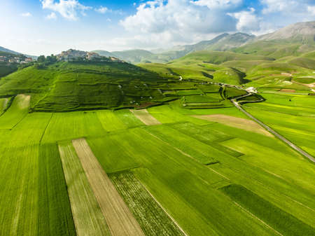 Aerial view of Piano Grande, large karstic plateau of Monti Sibillini mountains. Beautiful green fields of the Monti Sibillini National Park, Umbria, Italy.の写真素材