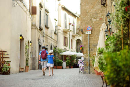 Father and daughter exploring the famous Orvieto, a medieval hill town, rising above the almost-vertical faces of tuff cliffs and surrounded by its vineyards and wineries in Umbria, Italy.の写真素材