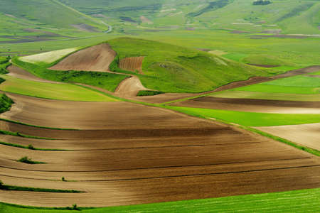 Piano Grande, large karstic plateau of Monti Sibillini mountains and one of the greatest tourist attractions in the area. Beautiful green fields of the Monti Sibillini National Park, Umbria, Italy.の写真素材