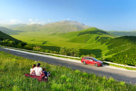 Family of three exploring the Piano Grande, large karstic plateau of Monti Sibillini mountains and one of the greatest tourist attractions in the area. Monti Sibillini National Park, Umbria, Italy.の写真素材