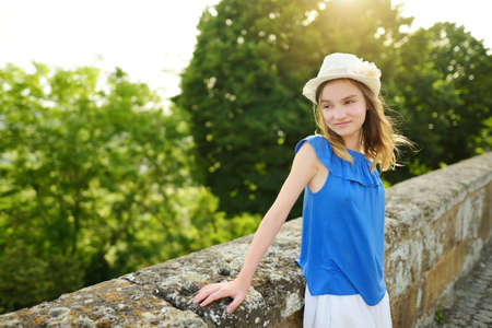 Cute young girl in white hat having fun outdoors on sunny summer evening. Child exploring nature. Summer activities for kids.の写真素材