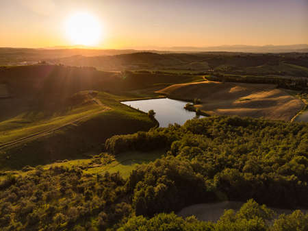 Stunning morning view of fields and farmlands with small villages on the horizon. Summer rural landscape of rolling hills, curved roads and cypresses of Tuscany, Italy.の写真素材