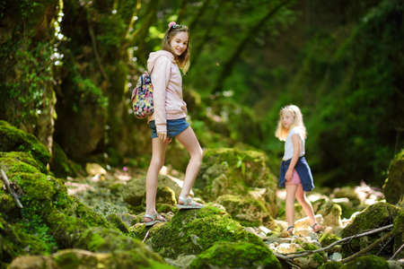 Young girls hiking in Botro ai Buchi del Diavolo, rocky gorge hiking trail, leading along dried up river. Beautiful footpath extending into the woods near San Gimignano town, Tuscany, Italy.の写真素材