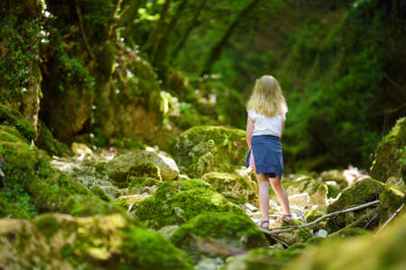 Young girl hiking in Botro ai Buchi del Diavolo, rocky gorge hiking trail, leading along dried up river. Beautiful footpath extending into the woods near San Gimignano town, Tuscany, Italy.の写真素材