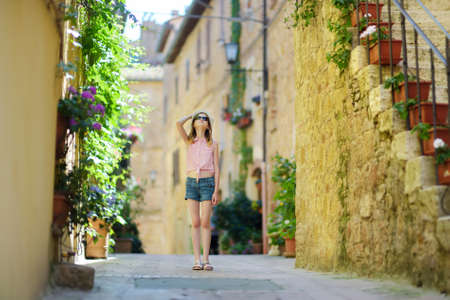 Young girl exploring in Pienza, a village located in the beautiful Tuscany valley, known as the 'ideal city of the Renaissance' and a 'capital' of pecorino cheese. UNESCO World Heritage Site.の写真素材