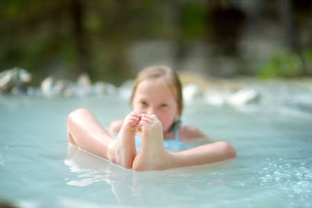 Young girl bathing in Bagni San Filippo, small hot spring containing calcium carbonate deposits,...