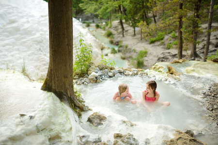 Young girls bathing in Bagni San Filippo, small hot spring containing calcium carbonate deposits,...