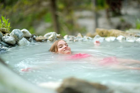 Young girl bathing in Bagni San Filippo, small hot spring containing calcium carbonate deposits, which form white concretions and waterfalls. Geothermal pools and hot springs in Tuscany, Italy.の写真素材