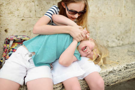 Two sisters exploring old narrow streets of famous Montepulciano town, located on top of a limestone ridge surrounded by vineyards. Tuscany, Italy.の写真素材