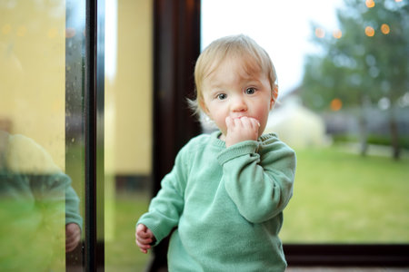 Adorable toddler boy standing by the window. Toddler learning how to stand up unassisted.