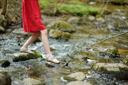Adorable young girl having fun during a hike in the woods on beautiful sunny spring day. Active family leisure with kids. Kid exploring nature.のeditorial素材