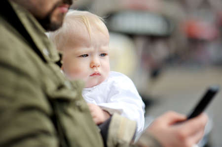 Cute little girl in her fathers arms. Dad and daughter having fun on sunny summer day in the city....