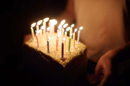 Homemade birthday cake with lots of candles in a dark room. Celebrating birthday at home.