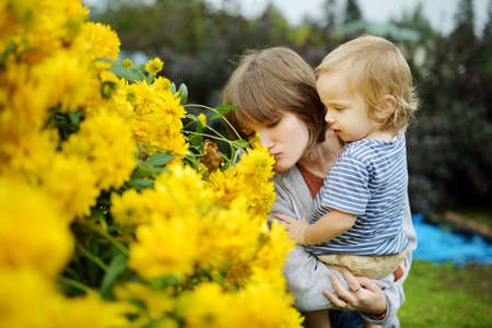 Young girl and her brother admiring bright yellow flowers of rudbeckia, commonly known as coneflowers or black eyed susans, in a sunny summer garden. Rudbeckia fulgida or perennial coneflower.の写真素材