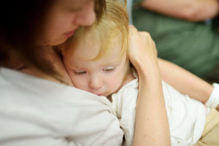 Cute funny toddler boy in his mothers arms. Mom and son having fun on sunny autumn day in a park. Adorable son being held by his mommy.の写真素材