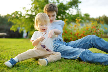 Funny toddler boy and his older sister having fun outdoors on sunny autumn day. Children exploring nature. Autumn activities for small kids.の写真素材