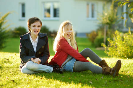 Two cute young sisters having fun together on beautiful autumn day. Active family leisure with kids. Family fun outdoors.の写真素材