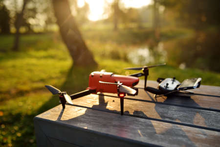 A drone ready to take off from a wooden bench in a park on sunny autumn morning.