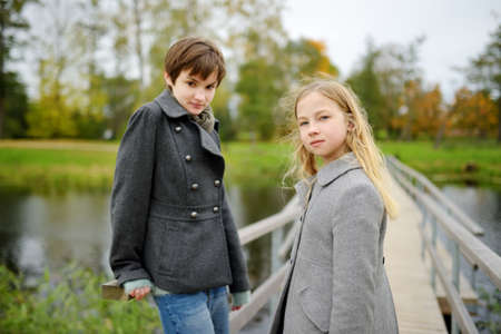 Two cute young sisters having fun together on beautiful autumn day. Active family leisure with kids. Family fun outdoors.の写真素材
