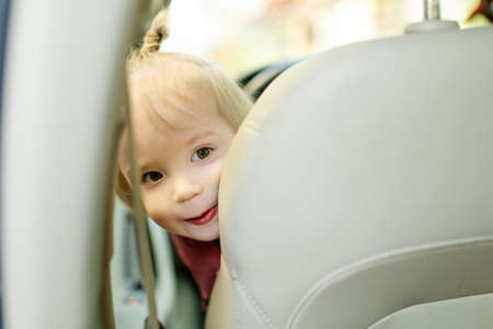 Adorable toddler boy playing in the driver's seat. Cute little son sitting in fathers car. Small child having fun in a vehicle.の写真素材