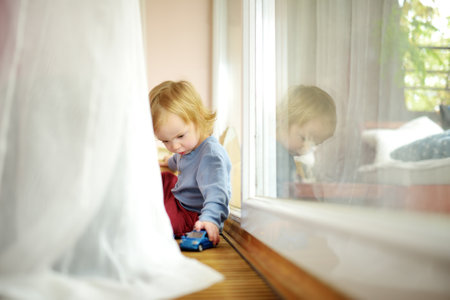 Cute toddler boy playing with blue toy car at home. Small child having fun with toys. Kid spending...