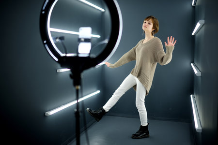 Beautiful teenage girl taking a selfie picture with mobile phone in light of the ring lamp. Trend, technology, beauty, fashion concept.の写真素材