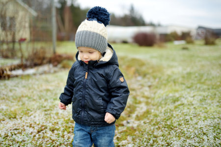 Funny toddler boy having fun outdoors on chilly winter day. Child exploring nature. Winter...