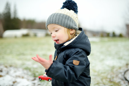Funny toddler boy having fun outdoors on chilly winter day. Child exploring nature. Winter activities for small kids.の写真素材