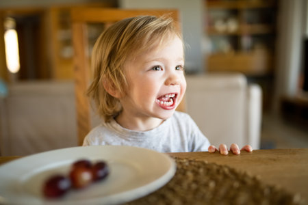 Cute little toddler boy eating grapes at home. Fresh organic frutis for infants. Healthy nutrition...