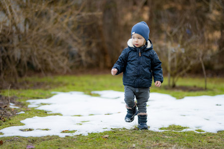 Funny toddler boy having fun outdoors on chilly winter day. Child exploring nature. Winter activities for small kids.の写真素材