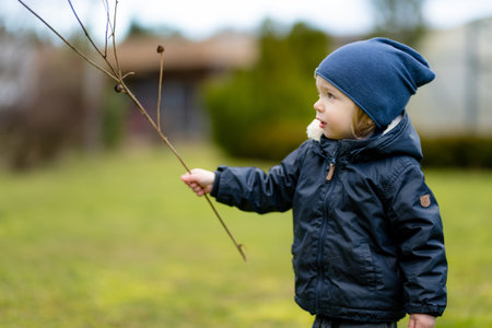 Funny toddler boy having fun outdoors on chilly winter day. Child exploring nature. Winter...