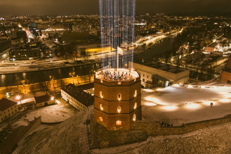 Scenic aerial view of Gediminas tower in Vilnius Old Town beautifully illuminated for 699th birthday celebration. Main symbol of Lithuanian capital at winter night.のeditorial素材
