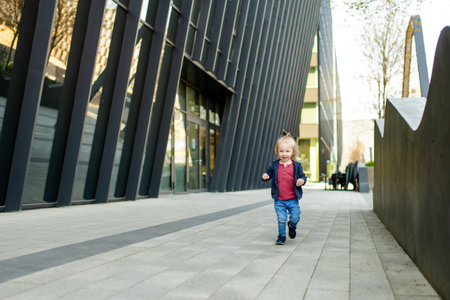 Funny toddler boy having fun outdoors on sunny spring day. Child in the city. Kid playing in a city park. Active leisure for families with kids.の写真素材