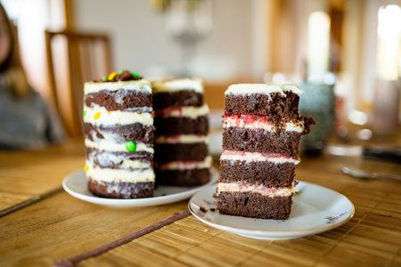 A slice of homemade layered birthday cake. Cutting chocolate birthday cake with white frosting....
