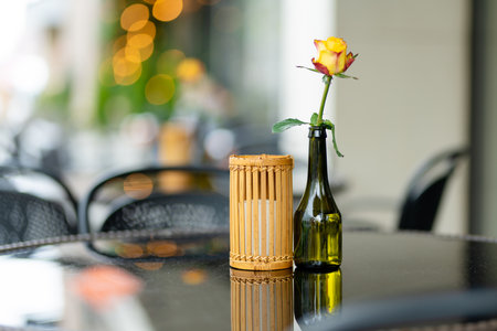 Outdoor restaurant table beautifully decorated with rose flower in a bottle in Vilnius, Lithuania, on nice summer day. Dining outdoors.の写真素材
