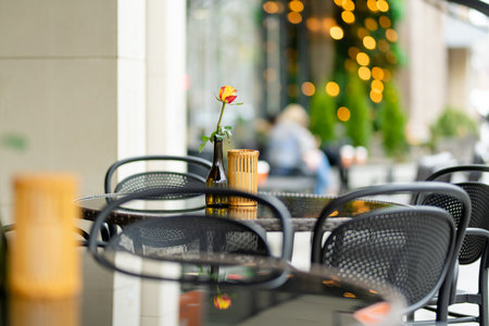 Outdoor restaurant table beautifully decorated with rose flower in a bottle in Vilnius, Lithuania, on nice summer day. Dining outdoors.の写真素材