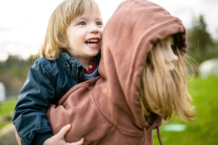 Cute big sister cuddling with her toddler brother. Adorable preteen girl piggybacking her small sibling. Children with large age gap. Siblings getting along.の写真素材