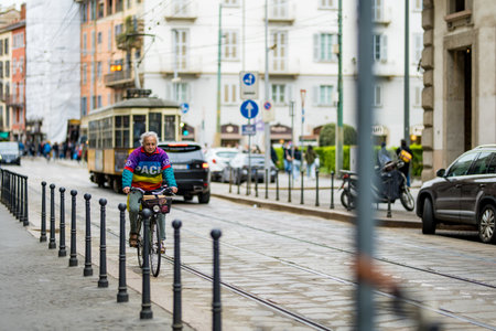 MILAN, ITALY - APRIL 2022: Man riding a bicycle on busy street in the center of Milan, a metropolis in Italy's northern Lombardy region. Milan, Lombardy, Italy.のeditorial素材