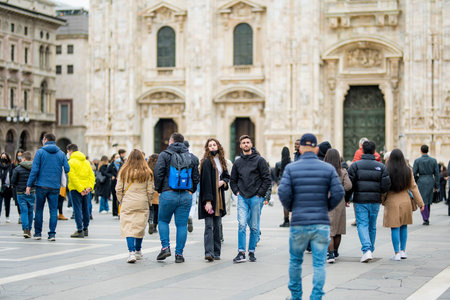 MILAN, ITALY - APRIL 2022: A group of people having fun, taking pictures and feeding the pigeons on the Cathedral Square or Piazza del Duomo in the center of Milan, Lombardy, Italy.のeditorial素材
